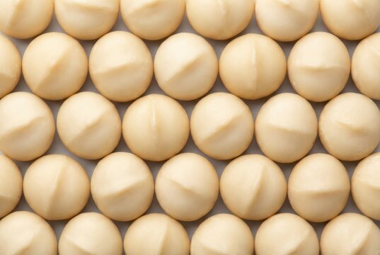 Round beige confectionery spheres arranged meticulously in uniform pattern highlighting texture and subtle sheen creating a visually striking minimalist composition