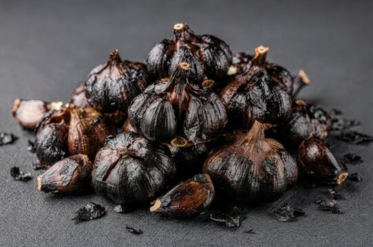 Black garlic bulbs with rich umami flavor displayed in artistic arrangement highlighting unique textures and culinary potential for gourmet cuisine and holistic health