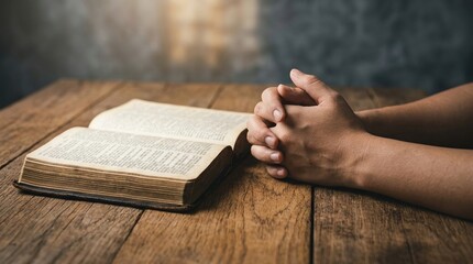 Naklejka premium prayer, bible, faith, hands, religion, spiritual, christianity - A person praying with clasped hands beside an open vintage holy book on a rustic wooden table in a peaceful, dim light.