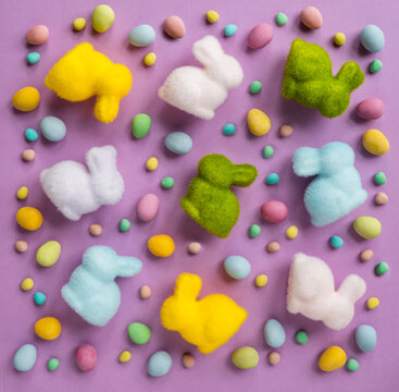 Top view many colorful Easter bunnies  and eggs on purple background.