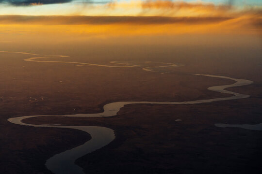 Winding river seen from airplane during sunset flight.