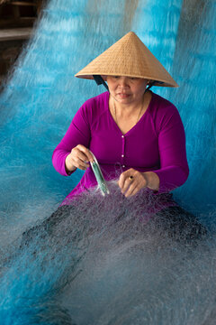 Woman repairing fishing nets in Vietnam