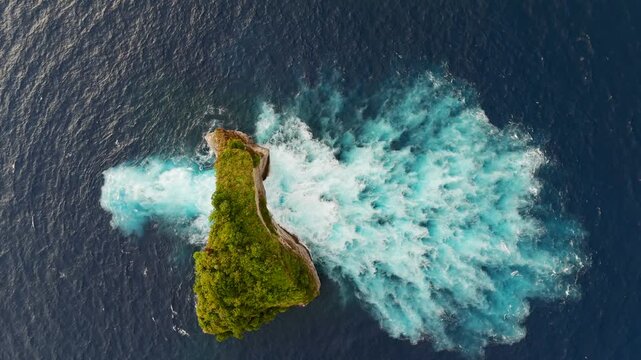 Overhead drone shot of powerful ocean waves flowing through natural rock arch, abstract blue water texture, Bali tropical island.