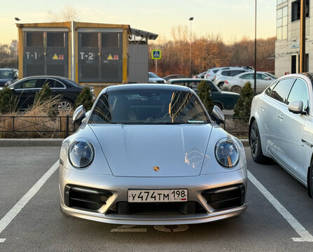 Silver Porsche 911 Carrera 4S VIII 992, sports car parked at the city street. Silver coupe sport car Porsche 911 Carrera 4S VIII 992 on parking lot. Exterior of a German sport car Porsche 911.