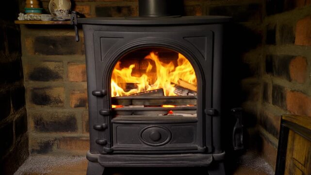 A lit wood burning stove in a brick fireplace