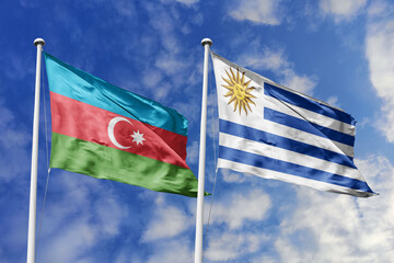 Fototapeta premium Azerbaijan and Uruguay flags waving in a clear blue sky, symbolizing a powerful diplomacy, expanding global trade, a strategic partnership, and a shared vision of unity for a sustainable future.