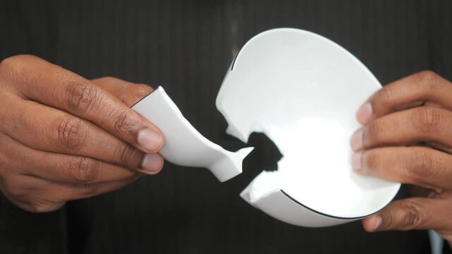 Person holds broken ceramic bowl in hands