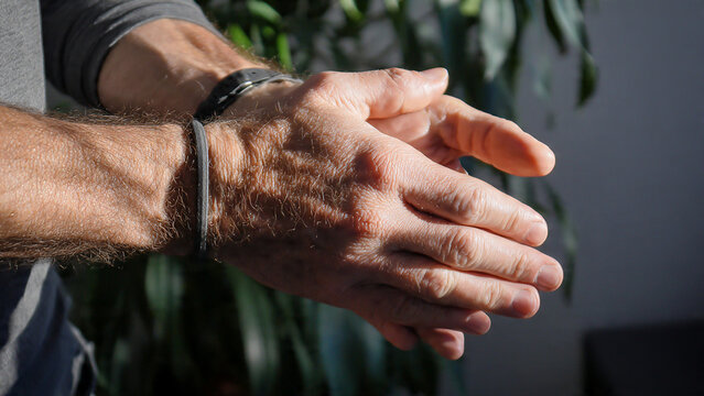 Close-up of hands, one with a watch, bathed in warm sunlight