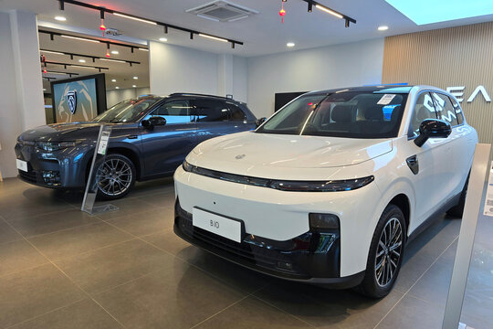 Penang, Malaysia - Feb 20, 2026: A front three-quarter view of a white Leapmotor B10 and a dark blue Leapmotor C10 SUV on display in a brightly lit car dealership.