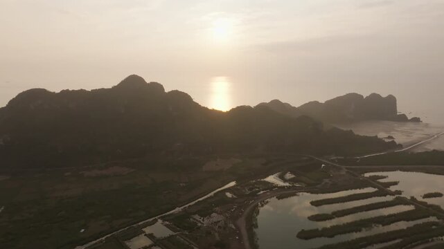 Cat Ba Vietnam drone move revealing the coastline beyond karst hills, with reflective ponds and muddy flats below.