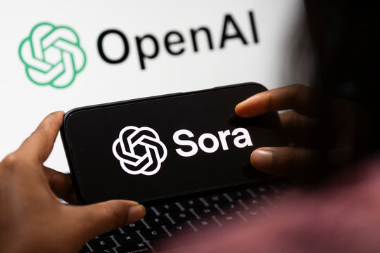 In this photo illustration, a smartphone displays the Sora AI logo in landscape orientation, with the OpenAI logo visible in the background