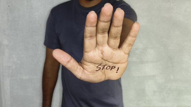 Male person hand with stop word written on palm. Sign of protest against sexual and racial discrimination. Depression, anxiety, abuse, violence, schizophrenia, suffering and mental harassment concept.
