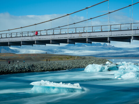 Visitor on the bridge carrying route 1 over Glacier Lagoon in Iceland with icebergs floating underneath