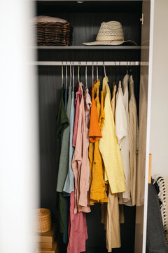Colorful clothing hanging in wardrobe representing fast fashion overload