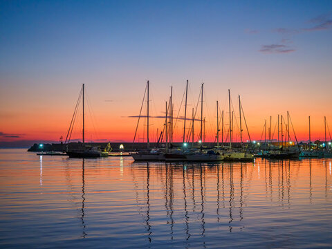 Sailboats moored in Sciacca marina reflecting vibrant sunset colors
