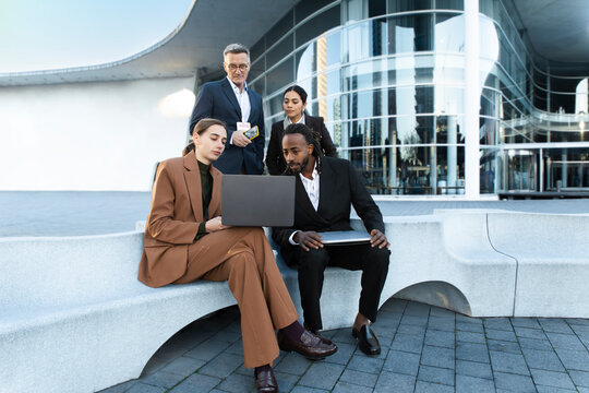 Team of business professionals working with laptop outdoors