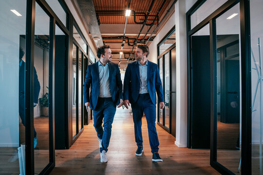 Businessmen walking and conversing in a modern office corridor
