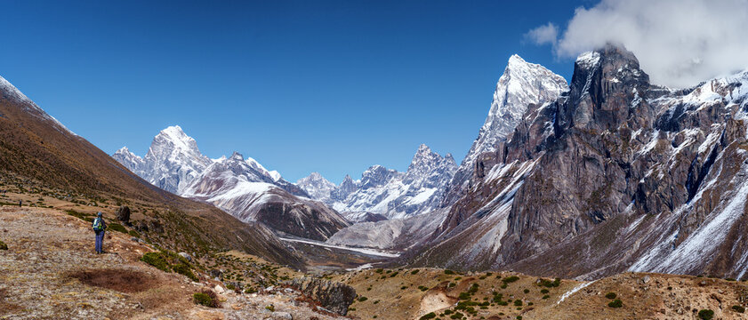 Woman hiker backpacker admiring panoraic landscape on trail during on her trek to Everest Base Camp in Nepal. Beautiful inspirational panoraic landscape, trekking and activity.
