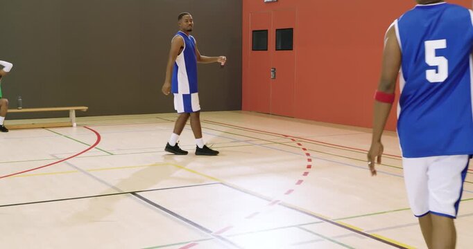 Pressuring defender sparking african american player dribbling ball up court crossover toward hoop