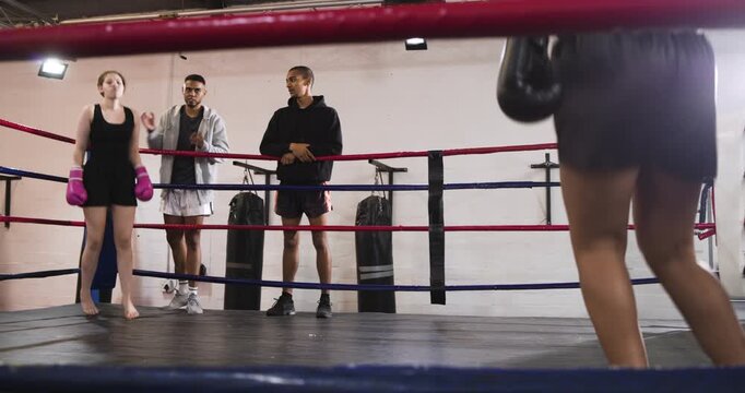 Listening to coach guidance teenage boxer and female opponent are sparring for training in gym ring