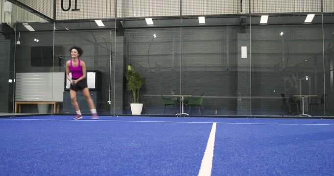 Diverse women players on padel court with rackets reacting to bounce lunging forehand, celebrating