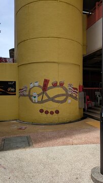 Kuala Lumpur, Malaysia - 2 December 2025: Vibrant Street Art Mural Painted on Yellow Curved Pillar Featuring Maneki Neko Lucky Cat, Chinese Lanterns, and Lion Dance Symbols in Chinatown Urban Area for