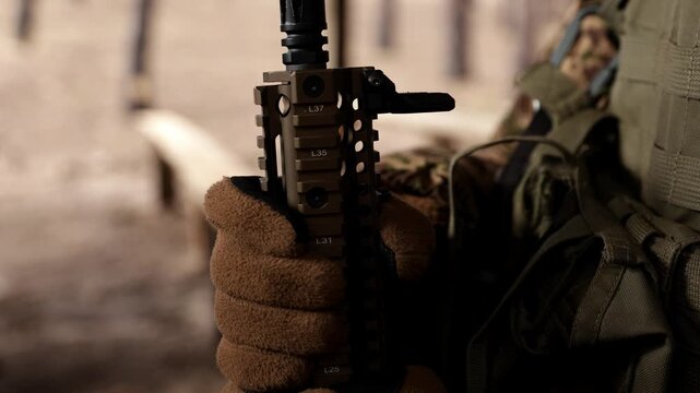 Detailed horizontal close-up of a soldier's hand in a tactical glove holding a modern rifle featuring a picatinny rail system for mounting accessories