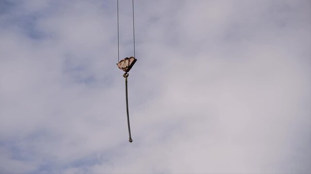 Block on the cable of a tower crane with hooks against the background of the sky