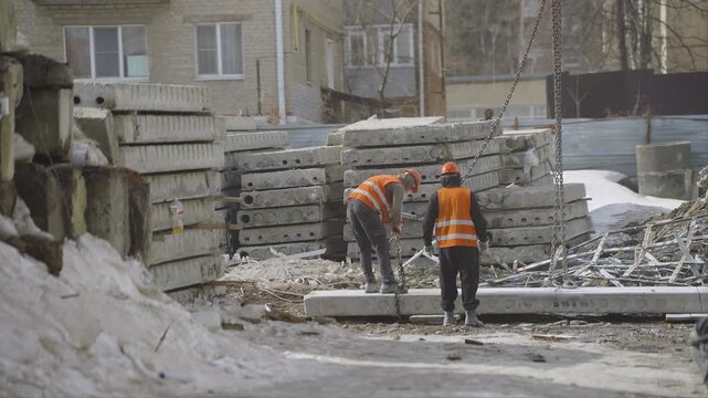 Slingers hook a concrete floor slab to the crane