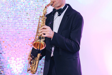Naklejka premium young man in black smoking playing saxophone, cropped, unrecognizable