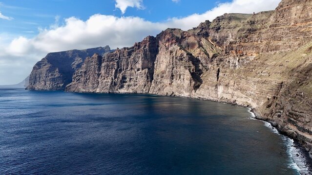Majestic Los Gigantes cliffs in Tenerife overlooking the calm ocean on a sunny day.