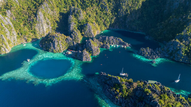 Aerial top-down drone view of the iconic Barracuda Lake in Coron, Palawan. A circular turquoise lagoon hidden within massive limestone karst formations in the Philippines