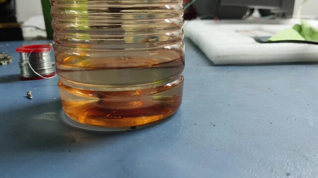 Thin liquid layers separating in glass jar with light sediment