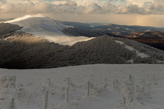 Breathtaking winter panorama of the Polonina Wetlinska ridge in Bieszczady Mountains, Poland. Snow-covered hiking trail with tourists in the distance