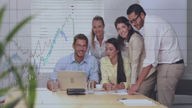 Team huddling at table, man pointing at sheet causing animated finance charts, group posing smiling