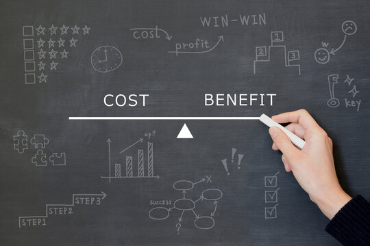 コストと利益のバランスを測るシーソーを黒板に描く人物の手