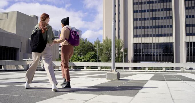 African American woman with purple backpack walking plaza when redhead woman running back greeting