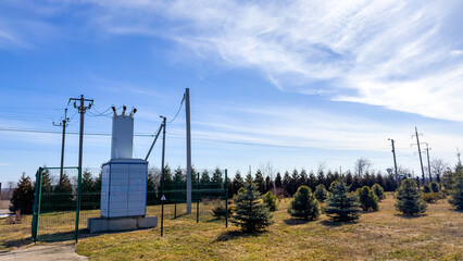Fototapeta premium Utility structure stands in open field. A utility structure is surrounded by young trees in an open area during a clear day with blue sky.