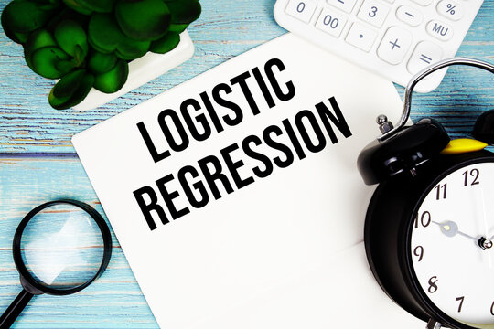 Logistic Regression written on paper placed on a blue wooden surface, alongside a magnifying glass, a clock, a calculator, and a small plant