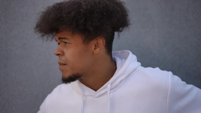 Young man with an afro hairstyle thinking with a worried expression. His initial anxiety gives way to a moment of thoughtfulness and then determination