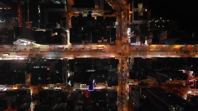 Overhead drone shot of illuminated streets and dark apartment buildings in Kowloon district in Hong Kong
