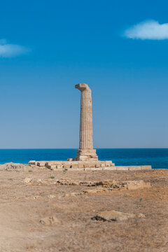 View of the ancient Column of Hera Lacinia standing on the rocky coast against the blue sea in Crotone, Calabria, Italy.