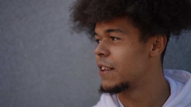 Close-up of a young black man with afro hair touching a lock of hair and making funny faces. His hairstyle is very voluminous and expressive