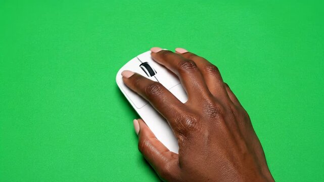Dark skinned male hand using white wireless computer mouse on isolated green screen chroma key background for technology product presentation or digital overlay use