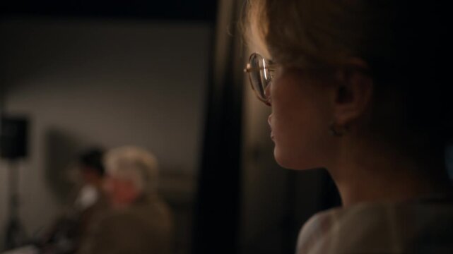 Tilt up shot of young adult female comic checking text of speech on clipboard revising script backstage while feeling nervous before show