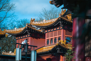 Fototapeta premium Traditional Chinese temple building with ornate golden roof and red walls against blue sky. Cultural architecture and travel destination concept.