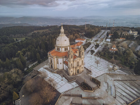 Aerial view of Santuario de Nossa Senhora do Sameiro's striking architecture contrasting against the lush green landscape under a soft, diffused light, Braga, Portugal.