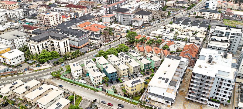 Aerial view of modern buildings, residential houses, and roads creating a dense urban landscape contrasting with green trees, Lagos, Lagos, Nigeria.