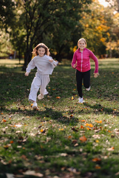 Happy girls running and playing in autumn park