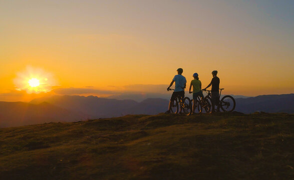 AERIAL: Unrecognizable friends watch the sunset after a mountain bicycle trip.